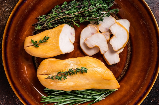 Hot Smoked chicken breast Poultry meat in a rustic plate with herbs