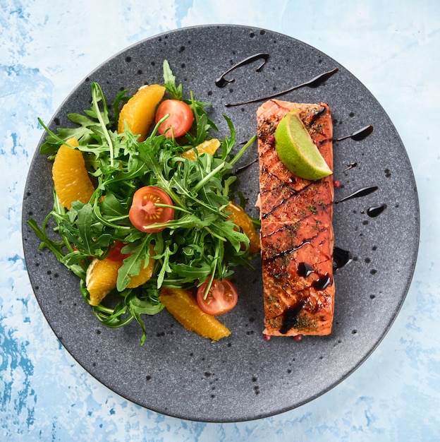 Hot smoked salmon with arugula salad, cherry tomato and orange. Healthy eating. Top view.