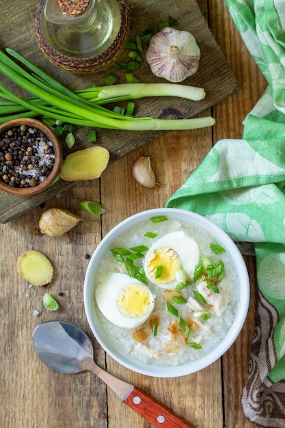 Hot soup chicken with ginger rice and garlic in a bowl on a rustic table Top view flat lay