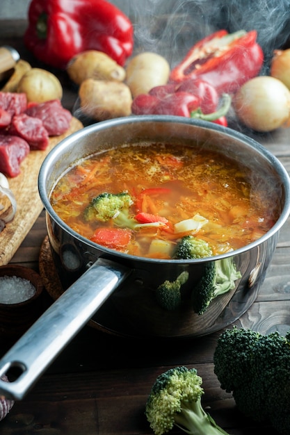 Дымится горячий суп в кастрюле. с говядиной и овощами. сытное, питательное блюдо. ужин