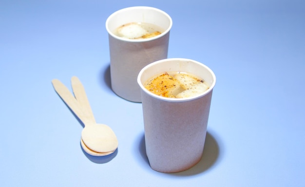 Hot soup to take away in a disposable paper bowl with wooden spoons