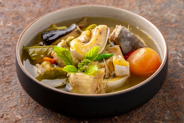 Zuppa calda e acida di pesce gatto gigante del mekong zuppa piccante chiara in ciotola di ceramica su sfondo texture arrugginito cibo tailandese tom yum pla buek tom yam pla buek