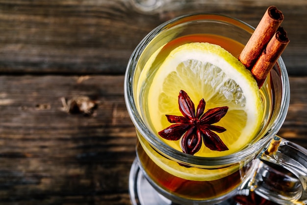 Hot spiced Apple cider Toddy with lemon honey and cinnamon stick in glass on wooden background