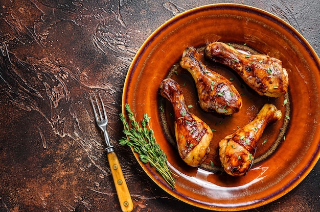 Hot and spicy bbq chicken drumsticks in a plate. Dark background.