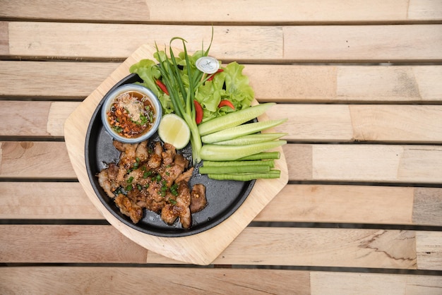 Hot and Spicy Grilled Pork Salad (Nam tok moo) on the wood table