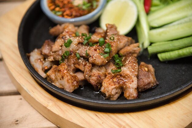 나무 테이블에 있는 뜨겁고 매운 구운 돼지고기 샐러드(Nam tok moo)