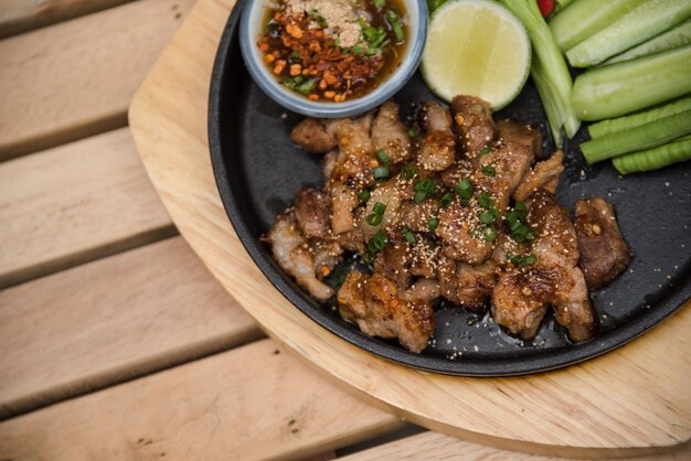 나무 테이블에 있는 뜨겁고 매운 구운 돼지고기 샐러드(Nam tok moo)