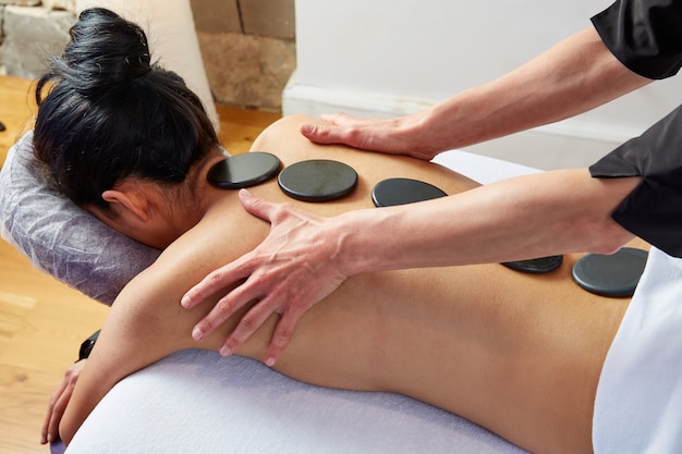 Hot stone massage in woman back physiotherapist