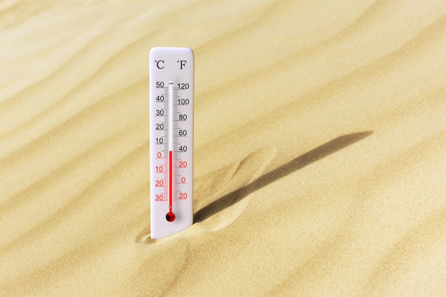 Foto caldo giorno d'estate termometro con scala celsius e fahrenheit nella sabbia temperatura ambiente più 5