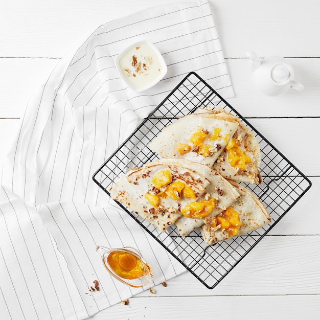 Hot sweet pancakes with peach on a square plate