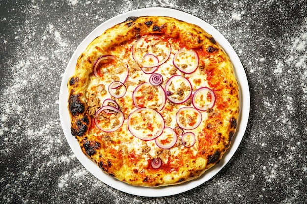 Pizza tradizionale gustosa calda con tonno su sfondo scuro
