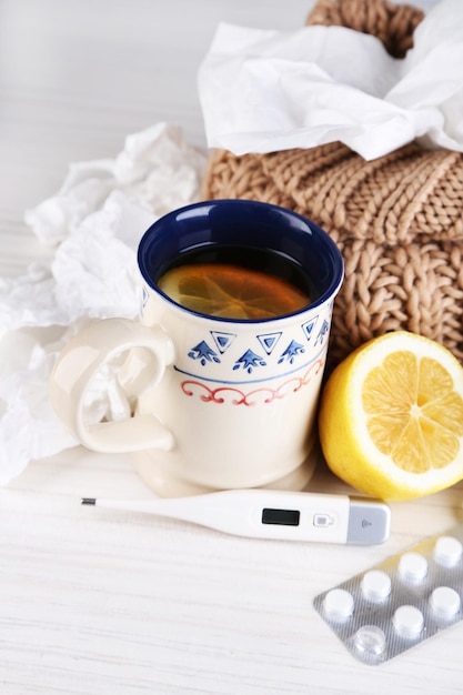 Photo hot tea for colds pills and handkerchiefs on table closeup