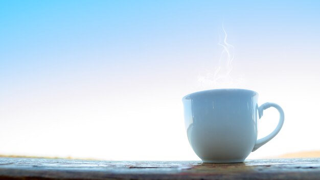 Hot tea cup top on wooden with sunset time.