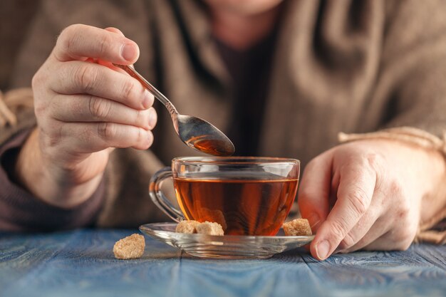 男性の手でガラスのコップで熱いお茶