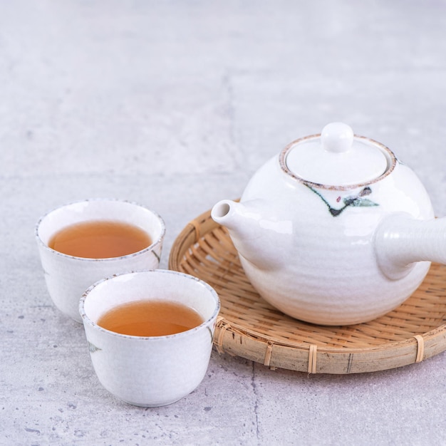 Горячий чай в белом чайнике и чашки на сите на ярко-сером цементном фоне крупным планом копируют концепцию дизайна пространства