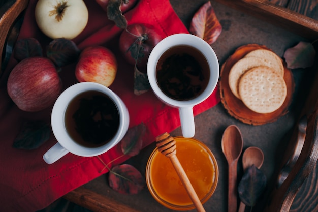 Hot tea with apples and honey on a wooden tray. Autumn harvest