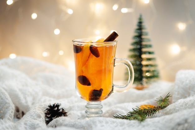 Hot tea with cinnamon, berries and oranges on a white wool blanket