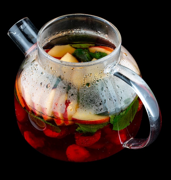 Hot tea with fruit and mint in a glass teapot On dark background