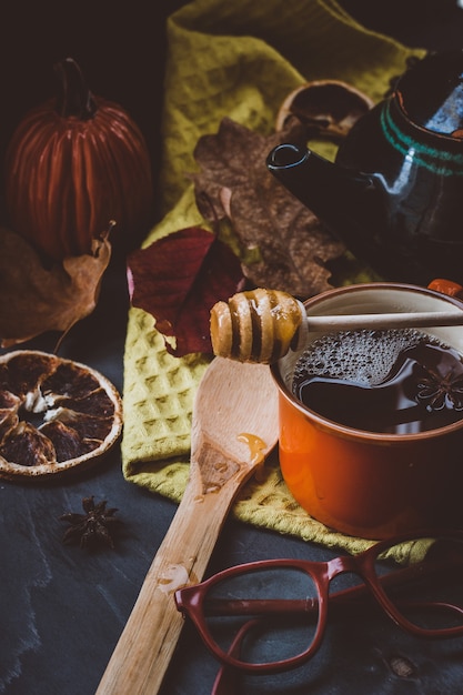 hot tea with honey and cinnamon in an orange Cup autumn atmosphere on a dark surface