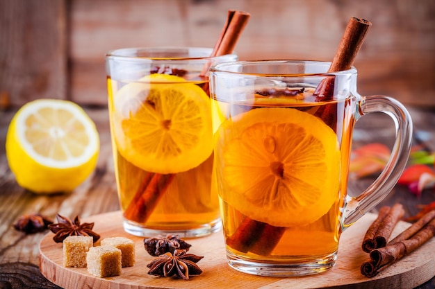 Hot tea with lemon anise and cinnamon in glass mugs on wooden table