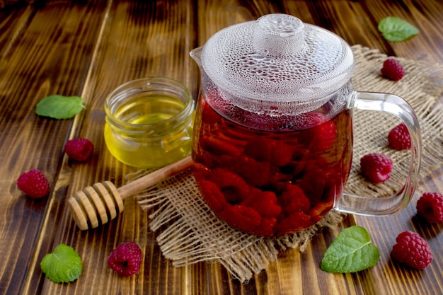 Hot tea with raspberries, honey and mint on the rustic  wooden background. Healthy drink.