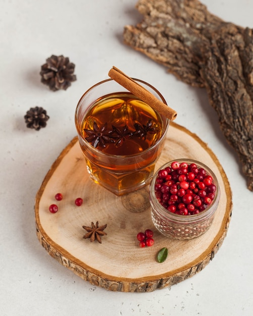 Hot tea with spices, Apple and berries in a transparent glass mug on a wooden stand. The concept of home comfort, autumn