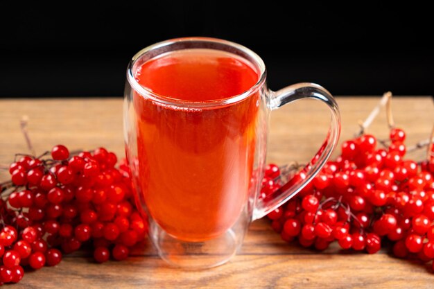 Hot viburnum tea in a glass cup with a double bottom on a black background