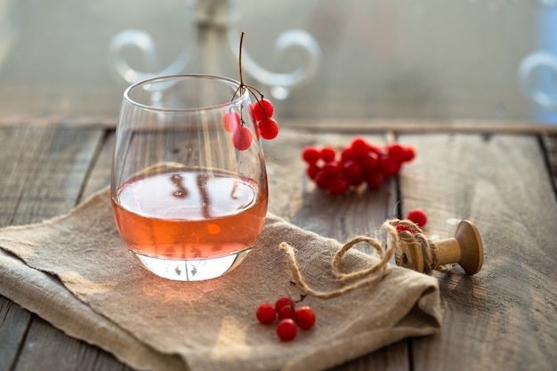 Hot viburnum tea in a glass with on a gray wooden table, next to fresh viburnum berries. viburnum healthy tea