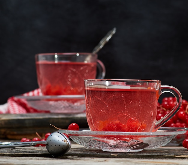 Hot viburnum tea in a transparent cup with a handle and saucer 