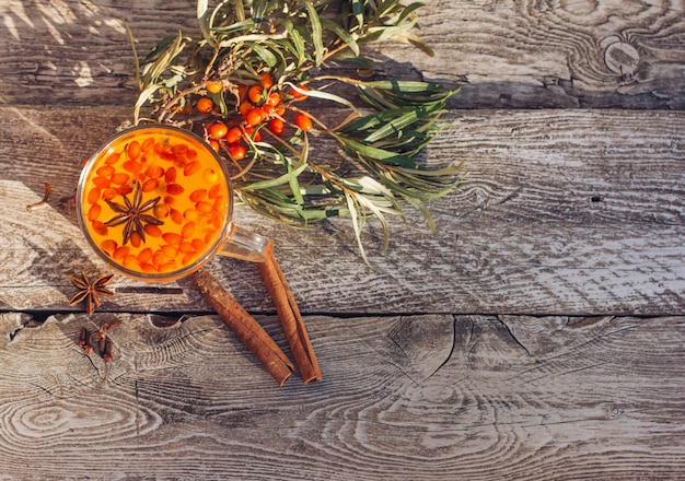 Hot vitamin Sea buckthorn tea into a cup, stands on an old woodenbackground. Relaxation and herbal medicine, anti-cold drink, flu season