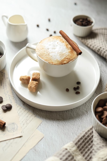 Bevanda calda al caffè con schiuma di latte e cannella in una tazza di caffè in grani, cioccolato e spezie