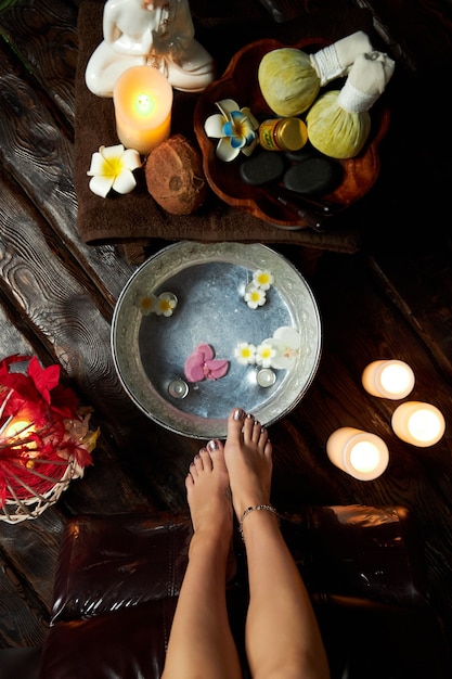 Foto acqua calda con fiori per piedi fumanti, cure termali, candele e frutta. foto di alta qualità