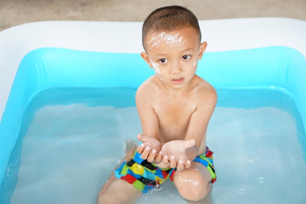 더운 날씨 욕조에서 즐겁게 물놀이를 하는 소년