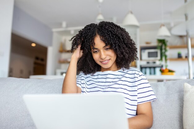 自宅のソファでラップトップに取り組んでいる若い女性のホット