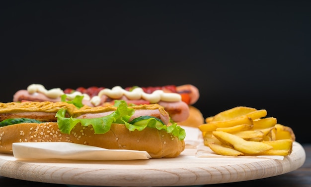 Hotdog gegarneerd met pittige mosterd en geserveerd met knapperige franse vuren op een rustieke houten bord op een donkere achtergrond met kopie ruimte