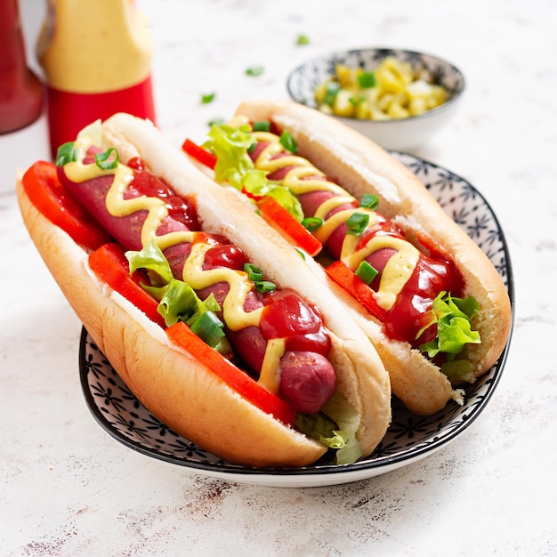 Hotdog met gegrilde worsttomaat en sla op lichte achtergrond Amerikaanse hotdog