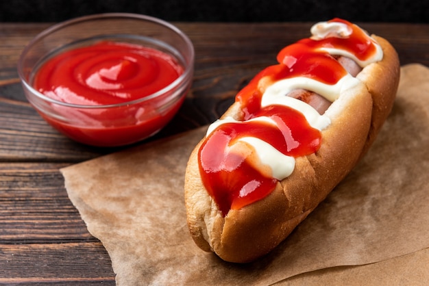 Hotdog met mayonaise en ketchup op donkere houten achtergrond.