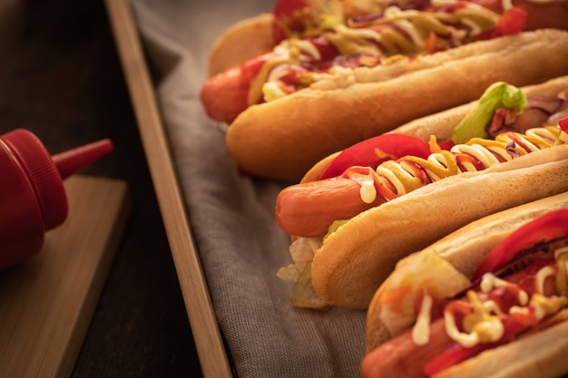 Hotdog met peper, tomaat, sla en salade mix op houten.