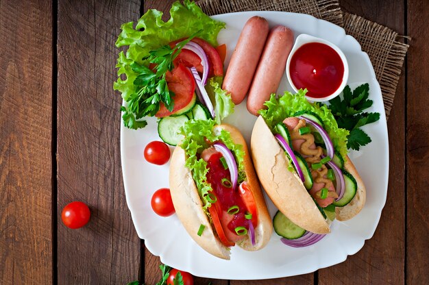 Hotdog with ketchup, mustard, lettuce and vegetables on wooden table