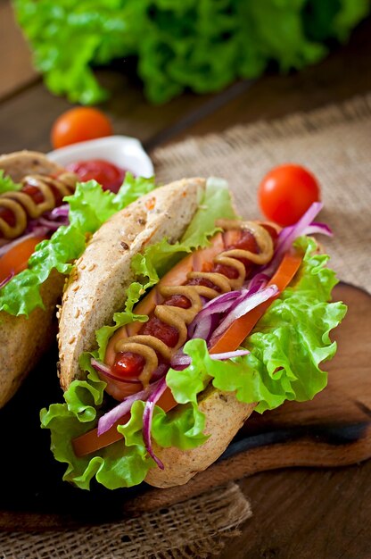 Hotdog with ketchup mustard and lettuce on wooden background