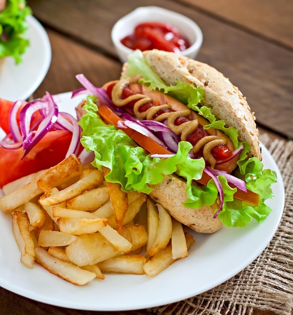 Hotdog with ketchup mustard and lettuce on wooden background