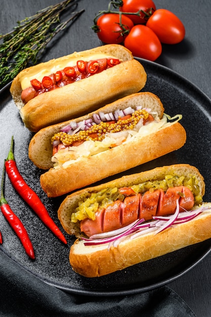Hotdogs met diverse toppings. Heerlijke hotdogs met varkens- en rundvleesworstjes. Zwarte achtergrond. Bovenaanzicht