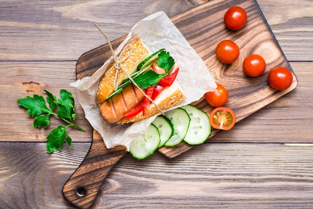 Hotdogs met sesambroodjes en verse groenten op een bord op een houten tafel