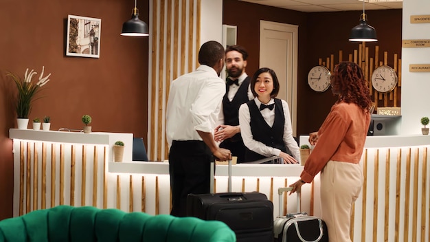 Photo hotel administrator handing guests booking reservation file to receptionists during check in. tourists being assisted by friendly concierge staff coworkers inside reception lobby