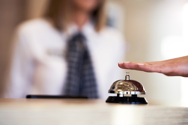 Hotel bell at front desk and receptionist in