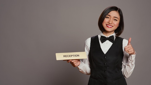 Photo hotel concierge holding sign to indicate direction for reception desk