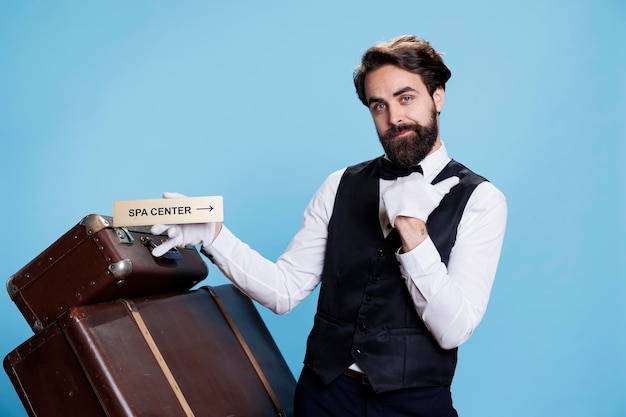 Hotel employee works in travel sector and leads visitors to the relaxation area using indication for the spa. Stylish man in formal attire indicating and displaying pointer with locations.