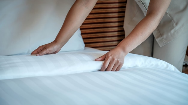 고급 호텔 방에서 침대를 만드는 호텔 메이드 손