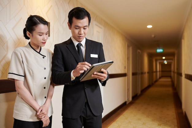 Менеджер отеля показывает служанке список комнат, которые нужно убрать для гостей.
