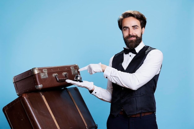 Hotel porter shows service bell, creating hotel concierge hospitality concept, ringing for assistance. Male bellhop or employee helping with baggage, luxury formal occupation.